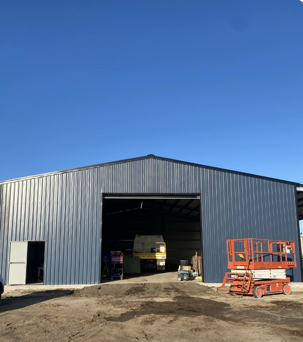 Large shed clad and roofed, scissor lift parked outside